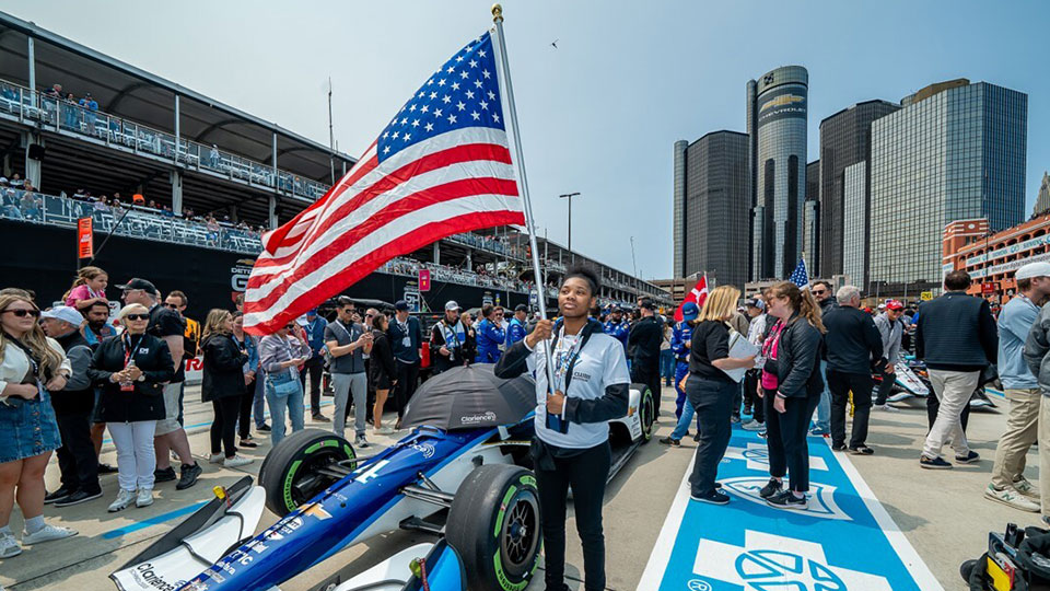 A child holds the American Flag on the starting grid